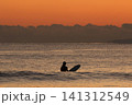 湘南鵠沼海岸  日没後の海で波待ちをするサーファー 141312549