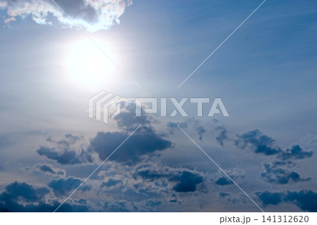 Bright sun shining in the blue sky surrounded by dark and light clouds Bright sun shining in the blue sky surrounded by dark and light clouds 141312620
