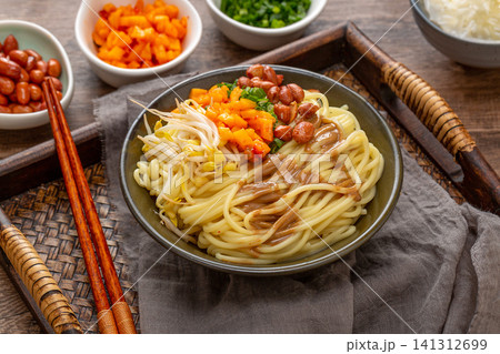 a bowl of traditional Wuhan hot dry noodles with sesame paste, peanuts and pickles on a wooden tray a bowl of traditional Wuhan hot dry noodles with sesame paste, peanuts and pickles on a wooden tray 141312699