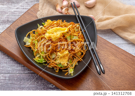 stir-fried Chinese alkaline noodles with cabbage served on a gray plate with a fork, modern food styling. stir-fried Chinese alkaline noodles with cabbage served on a gray plate with a fork, modern food styling. 141312708