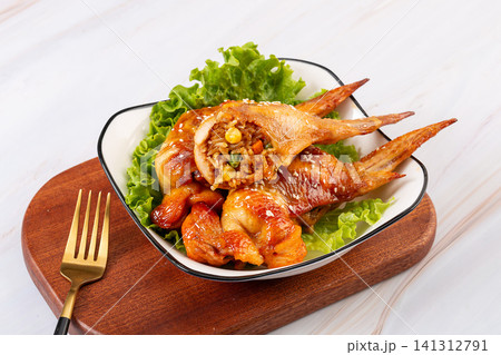 delicious grilled whole chicken wings stuffed with seasoned glutinous rice and vegetables, served on a plate with lettuce. delicious grilled whole chicken wings stuffed with seasoned glutinous rice and vegetables, served on a plate with lettuce. 141312791