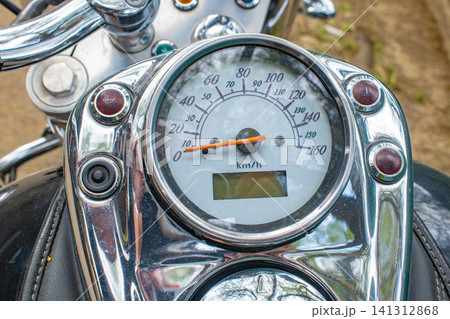 Close up of chrome motorcycle speedometer showing km scale with digital display, classic motorbike instrument concept Close up of chrome motorcycle speedometer showing km scale with digital display, classic motorbike instrument concept 141312868