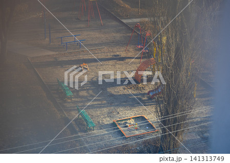 Empty neighborhood playground with swings and benches seen from high angle during sunny winter day, portraying quiet urban residential life and childhood recreation in public space Empty neighborhood playground with swings and benches seen from high angle during sunny winter day, portraying quiet urban residential life and childhood recreation in public space 141313749