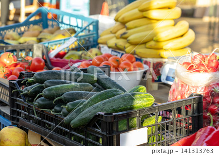 Fresh cucumbers in black plastic crates at an outdoor farmers market, showcasing ripe vegetables and fruits displayed for sale, conveying healthy nutrition and local agriculture Fresh cucumbers in black plastic crates at an outdoor farmers market, showcasing ripe vegetables and fruits displayed for sale, conveying healthy nutrition and local agriculture 141313763