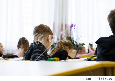 Young students sit at desks in an elementary school classroom focusing on their daily lessons to represent the academic environment, diligent learning, and growth in education Young students sit at desks in an elementary school classroom focusing on their daily lessons to represent the academic environment, diligent learning, and growth in education 141313939