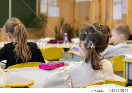 Young students sit at their desks in an elementary school classroom, focusing on daily lessons in a bright, academic environment that promotes childhood development and learning Young students sit at their desks in an elementary school classroom, focusing on daily lessons in a bright, academic environment that promotes childhood development and learning 141313941