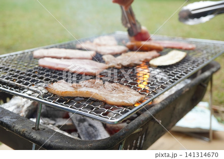 炭火バーベキューで肉を焼くアウトドア調理シーン 炭火バーベキューで肉を焼くアウトドア調理シーン 141314670