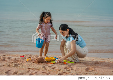 happy preschool child girl playing sand toy with mother on sea beach in Pattaya, Thailand happy preschool child girl playing sand toy with mother on sea beach in Pattaya, Thailand 141315005