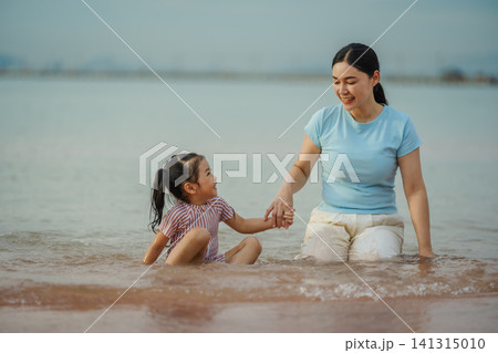 happy preschool child girl playing water with her mother on sea beach in Pattaya, Thailand happy preschool child girl playing water with her mother on sea beach in Pattaya, Thailand 141315010