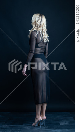 Young blonde dancer wearing transparent black dress and high heels posing in studio with black background Young blonde dancer wearing transparent black dress and high heels posing in studio with black background 141315206