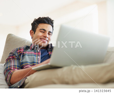 Man, laptop and sofa for relax connection with streaming service for free time, stress relief or resting. Male person, smile and couch with technology for online subscription, watching or internet 141315645