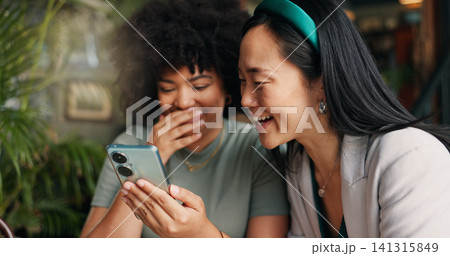 Happy women, friends and phone for social media at coffee shop for news, gossip or networking together. Young people smile and laughing on mobile smartphone for funny joke or meme at cafe restaurant 141315849
