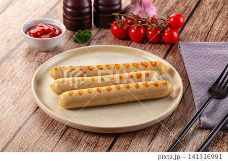 Grilled sausages on plate with cherry tomatoes and ketchup on wooden table 141316991