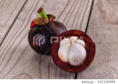 Mangosteen fruit whole and halved on wooden surface Mangosteen fruit whole and halved on wooden surface 141316999