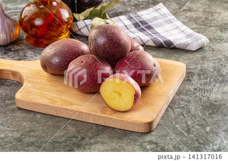 Red potatoes on wooden cutting board with garlic and oil 141317016
