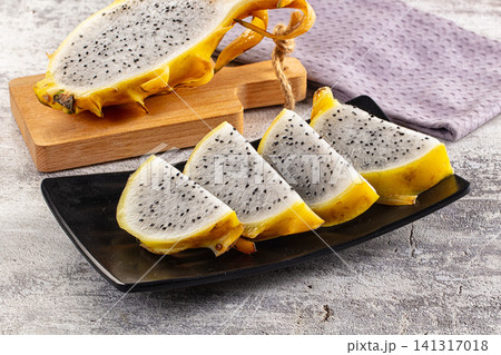 Sliced yellow dragon fruit on black plate with wooden cutting board Sliced yellow dragon fruit on black plate with wooden cutting board 141317018