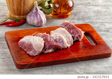 Raw duck breast pieces on wooden cutting board with garlic chili and oil Raw duck breast pieces on wooden cutting board with garlic chili and oil 141317031