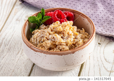 Oatmeal bowl with raspberries and mint on wooden table Oatmeal bowl with raspberries and mint on wooden table 141317045
