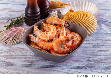 Cooked shrimp in bowl with seashells and herbs on rustic wooden surface Cooked shrimp in bowl with seashells and herbs on rustic wooden surface 141317061