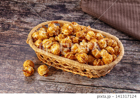 Caramel popcorn in woven basket on rustic wooden surface Caramel popcorn in woven basket on rustic wooden surface 141317124
