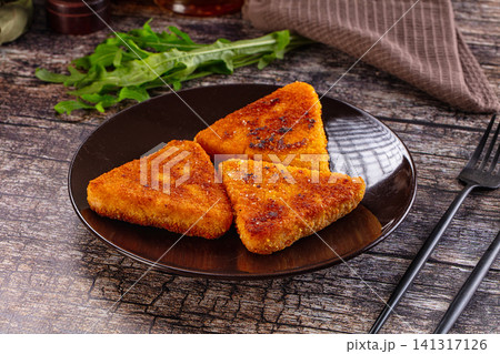 Crispy golden fried food triangles on dark plate with arugula and rustic wood background 141317126
