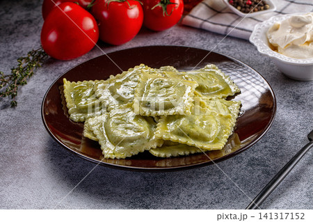 Ravioli with green herb sauce on dark plate with fresh tomatoes and cream Ravioli with green herb sauce on dark plate with fresh tomatoes and cream 141317152