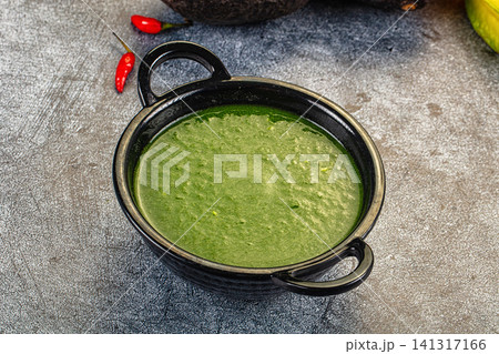 Green spinach cream soup in black ceramic bowl with red chili peppers on rustic surface Green spinach cream soup in black ceramic bowl with red chili peppers on rustic surface 141317166
