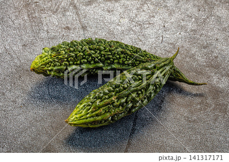 Two fresh green bitter melons on textured gray surface Two fresh green bitter melons on textured gray surface 141317171