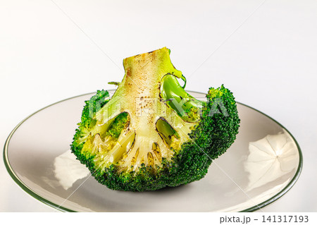 Grilled broccoli floret on ceramic plate with charred edges and vibrant green color 141317193