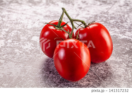 Three ripe red tomatoes on vine against textured gray background Three ripe red tomatoes on vine against textured gray background 141317232
