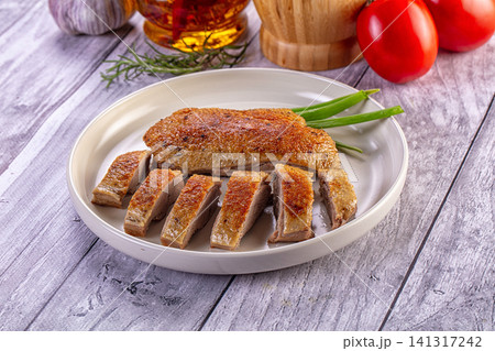 Crispy roasted duck breast sliced on white plate with green onions 141317242