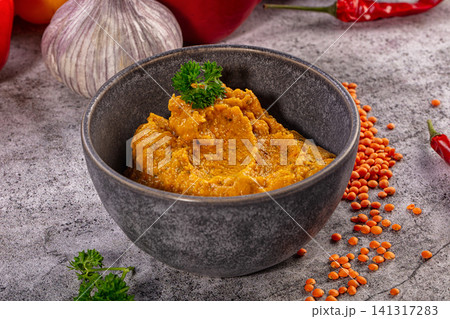 Spicy lentil curry in ceramic bowl with garlic and red chili peppers Spicy lentil curry in ceramic bowl with garlic and red chili peppers 141317283