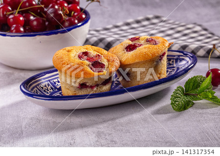 Cherry muffins on blue patterned plate with fresh cherries and mint Cherry muffins on blue patterned plate with fresh cherries and mint 141317354