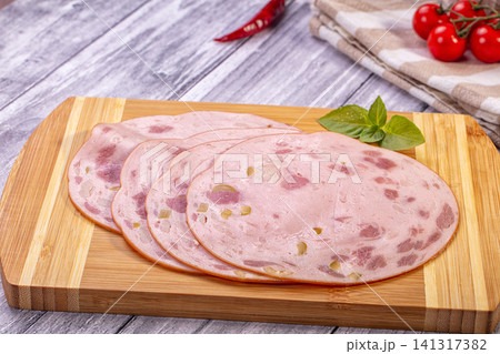 Sliced mortadella with basil on wooden cutting board Sliced mortadella with basil on wooden cutting board 141317382