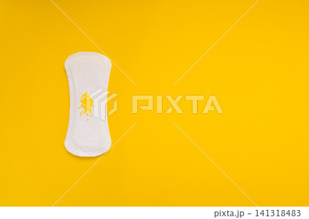 Sanitary Pad with Yellow Beads Symbolizing Urinary Leakage on Yellow Background Sanitary Pad with Yellow Beads Symbolizing Urinary Leakage on Yellow Background 141318483