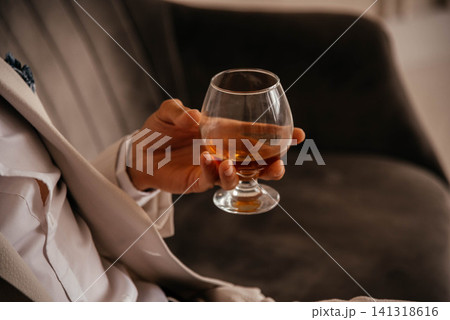 A glass of cognac in a man's hand. A glass of cognac in a man's hand. 141318616