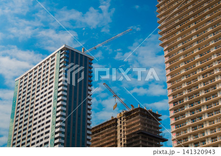 View of two yellow tower cranes and unfinished building construction 141320943