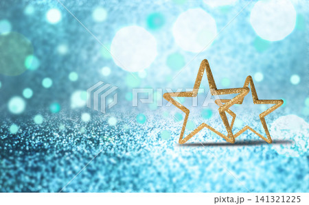 Close up photo of two golden star shaped outlines placed on a sparkling blue surface with bokeh light effects. 141321225