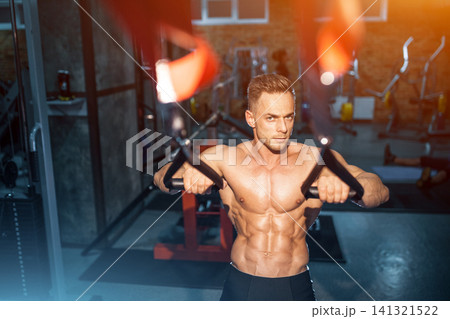 young man athlete with torso exercise and workout in gym with trx young man athlete with torso exercise and workout in gym with trx 141321522