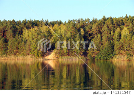 Beautiful river landscape with green forest reflected in the calm water surface. Beautiful river landscape with green forest reflected in the calm water surface. 141321547