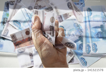 A woman's hand holds a crumpled Russian ruble banknote 141321578
