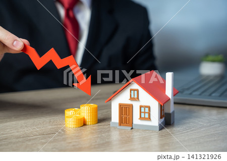 A private house and red downward arrow. Falling housing prices and declining property values in real estate market downturn and economic crisis A private house and red downward arrow. Falling housing prices and declining property values in real estate market downturn and economic crisis 141321926