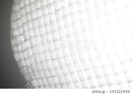 Photo of a large round softbox octobox of a studio professional lighting equipment with a constant source illuminating a square honeycomb. Angled side view 141322438