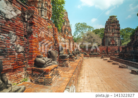 Ancient headless Buddha statues lining the red brick wall at Wat Mahathat in Ayutthaya, Thailand. 141322827