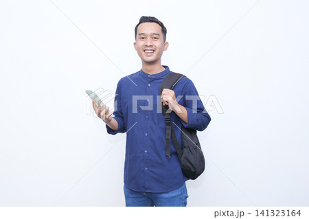 Man stares at phone with puzzled expression. He wears blue shirt and carries backpack. He holds phone while looking at screen. Background is plain white. Image conveys confusion or curiosity Man stares at phone with puzzled expression. He wears blue shirt and carries backpack. He holds phone while looking at screen. Background is plain white. Image conveys confusion or curiosity 141323164