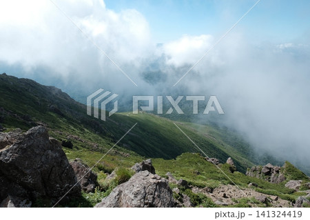 高山の稜線から見下ろす雄大な斜面と湧き上がる雲の絶景 高山の稜線から見下ろす雄大な斜面と湧き上がる雲の絶景 141324419