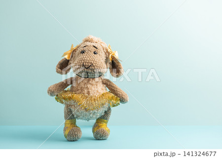 Knitted sheep ballerina toy standing on blue background 141324677