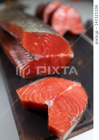 Smoked sockeye salmon fillets arranged on dark wooden board, rich red flesh, glossy surface, thin silver skin edge, and fine muscle lines in close detail, with salmon, smoked, sockeye, fillet detail Smoked sockeye salmon fillets arranged on dark wooden board, rich red flesh, glossy surface, thin silver skin edge, and fine muscle lines in close detail, with salmon, smoked, sockeye, fillet detail 141325106