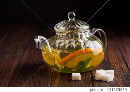 Glass teapot brewing citrus tea with orange and mint Glass teapot brewing citrus tea with orange and mint 141325680