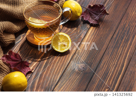 Warm tea with lemon and autumn leaves on wooden table Warm tea with lemon and autumn leaves on wooden table 141325692